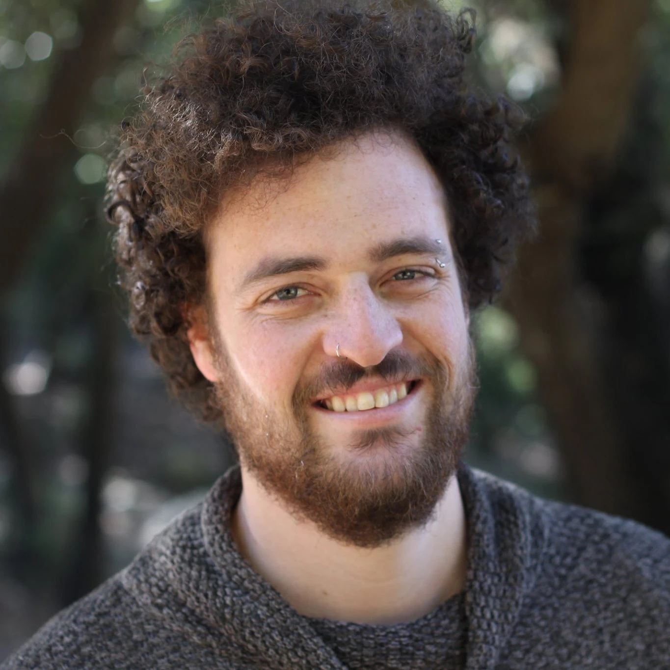 Portrait of a Avishai Karawan, a content creator, smiling outdoors, framed by trees in the background. Ideal for video editing projects involving royalty-free music and natural sound effects.